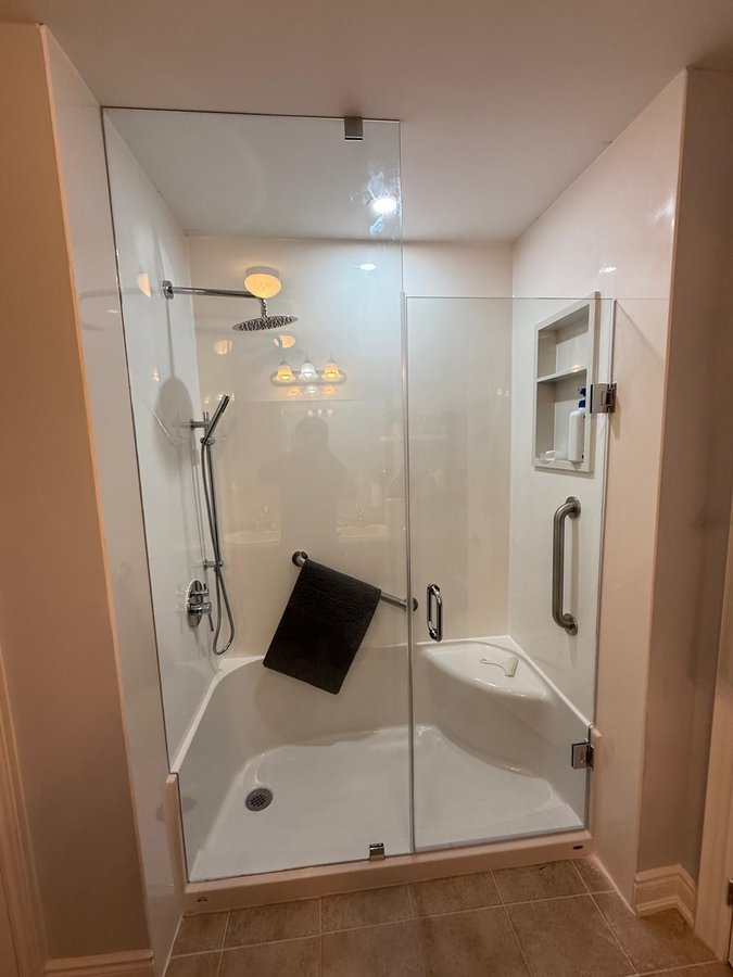 The walk-in shower Maurice built for Bill Beattie — frameless glass door, grab bars, built-in bench, handheld and rain shower heads