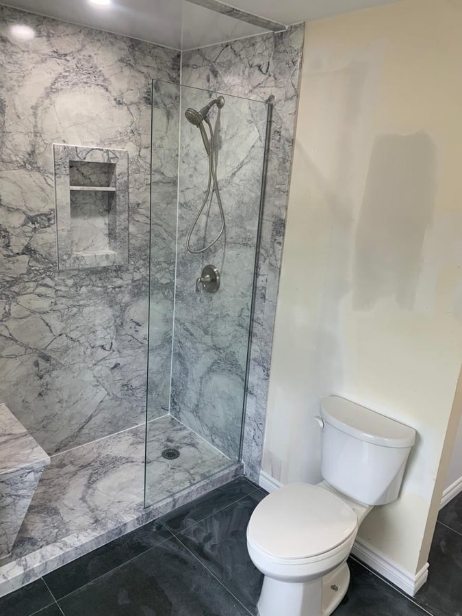 Walk-in shower with heavily-veined marble walls and inset niche