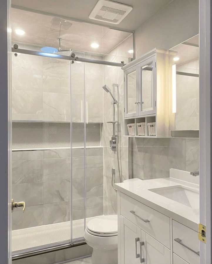 Full bathroom remodel featuring a walk-in shower with sliding glass doors, inset niche, and marble-look walls